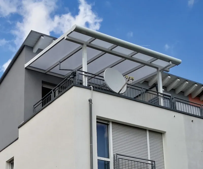 Weiße Balkonüberdachung mit Opal-Eindeckung über einem Dachgeschossbalkon mit Satellitenschüssel