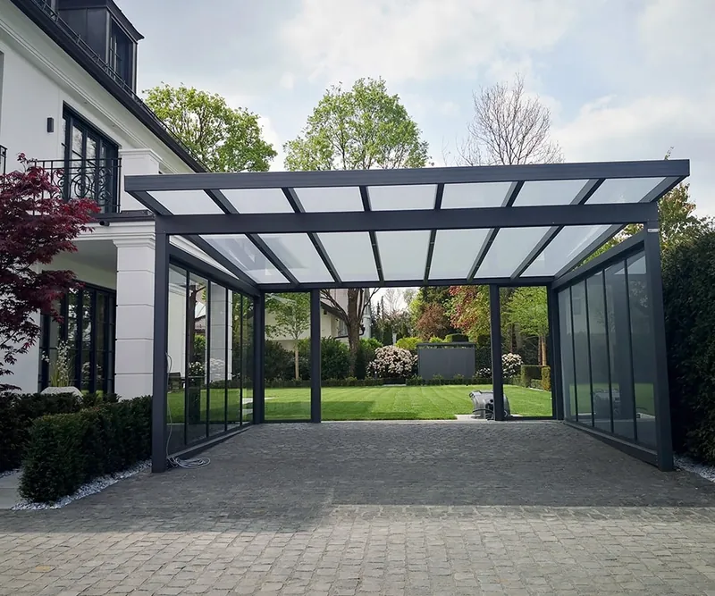 Freistehender Carport mit Pultdach aus Glas auf anthrazitfarbenen Stützen mit Glasschiebewand an der Seite vor einer Villa