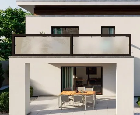Balkonbrüstung mit milchigem Verbundsicherheitsglas in schwarzem Rahmen an einem hellen Haus, darunter überdachte Terrasse mit Esstisch