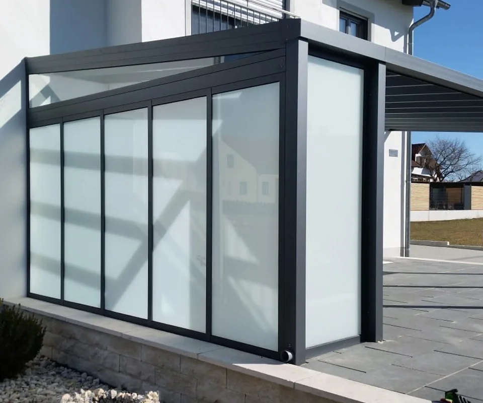 Terrassenüberdachung mit Seitenwand aus milchigen Glasfeldern in anthrazitfarbenem Rahmen