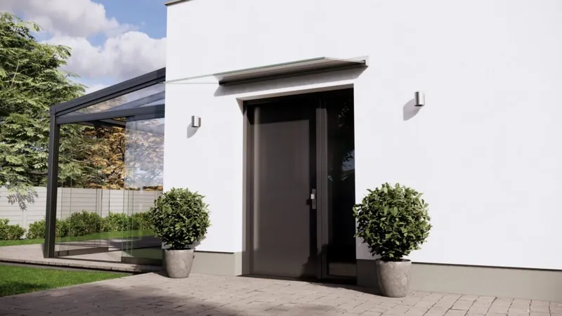 Schmales Glasvordach in eloxiertem Aluminium mit Klarglas über einer dunklen Haustür, links ein Buchsbaum